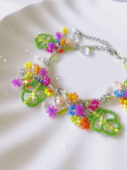 Handcrafted vibrant floral bracelet featuring green leaf patterns, colorful beads, luminous pearls, and moonstones, reflecting springtime elegance.